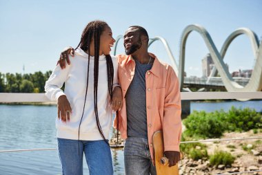 Sevgi dolu bir çift su kenarında gezer, sıcak bir tebessüm eder ve dışarıda eğlenir..