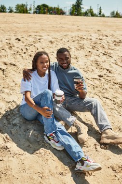 Neşeli bir çift el ele yürüyor, gülüşmeler ve kahkahalar paylaşıyor, doğal güzelliklerle çevrili..
