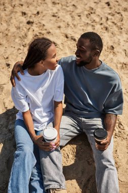 Sevgi dolu bir çift kumsalda sakin bir yürüyüş yapar, el ele tutuşur ve birlikte gülümserler..