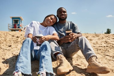 Genç bir çift kumsalda el ele gezer, kahkahalar atar ve aşklarını paylaşırlar..