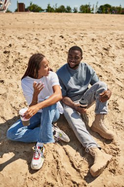 Mutlu bir çift sıcak kumların üzerinde kahve içip güneşin altında sohbet ediyor..