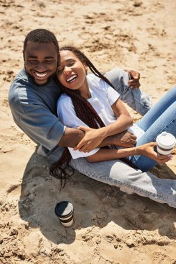 Genç çift, kumsalda rahatça yürürken sıcaklığı ve kahkahayı kucaklıyor..