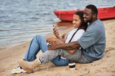 Sevgi dolu bir çift nehir kenarında el ele gezer, neşe ve neşeyi paylaşır..