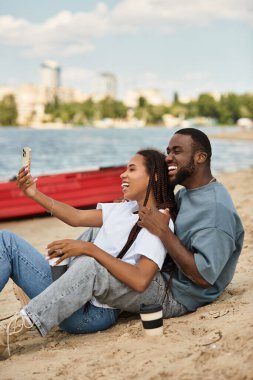 Sevgi dolu çift kumsalda rahatlar, selfie çekerken mutlu anıları yakalar..