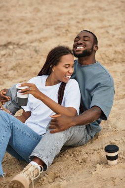 Genç bir erkek ve kadın el ele yürür, yüzleri neşe ve sevgiyle parlar..