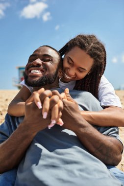 Genç çift sıcak kumsalda dinlenirken neşe ve kahkaha paylaşıyor..