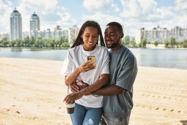 Birbirini seven çiftler neşeyle kucaklaşır. Nehir kıyısında parlak bir gökyüzünün altında bir anı paylaşırlar..