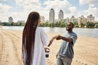 Neşeli bir çift nehir kıyısında el ele yürür, aşk ve kahkaha anlarını paylaşırlar..