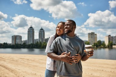 Genç bir çift mavi gökyüzünün altında suyun altında yürürken kahkaha ve sıcaklığı paylaşıyor..