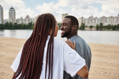 Nehir kıyısında birlikte gezen mutlu bir çift, gülüşlerini ve gülüşlerini gün ışığında paylaşıyor..