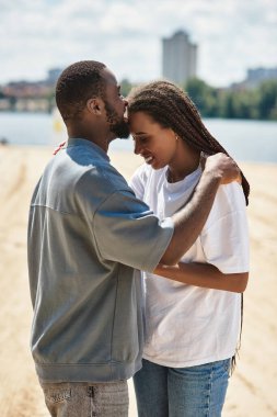 Bir çift birlikte yürür, sıcacık gülümseyerek dışarıda güzel bir günün tadını çıkarırlar..