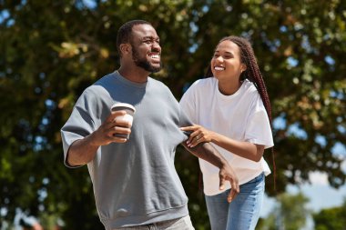 Sevgi dolu bir çift, neşeli bir caddede yürüyor, kahkahalarını paylaşıyor ve dışarıda neşe dolu anlar yaşıyor..