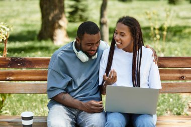 Yeşilliklerle çevrili bir bankta birlikte neşeli bir kahkahayı paylaşıyorlar..