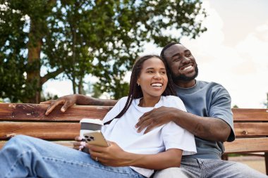 Genç çift, sakin bir açık havada el ele yürürken neşeli bir anı paylaşıyor.