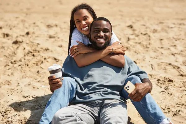 Genç çift kumsalda oturur, neşe dolu anları paylaşırlar kahkahalar ve bağlarla dolu.