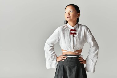 Genç Asyalı bir kadın mavi saçlarını ve modaya uygun kıyafetlerini sergiliyor..