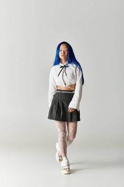 Kendine güveni tam, mavi saçlı, şık bir elbise giymiş modern modaya bürünmüş genç bir kadın..