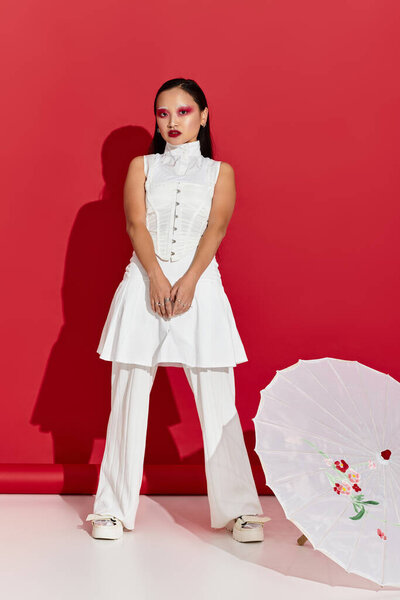 Молодая женщина представляет свои красочные глаза макияж и шикарный наряд, излучающий уверенность.