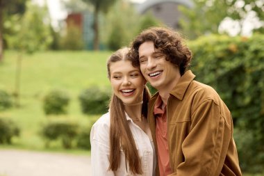 Neşeli bir çift el ele gezer manzaralı bir parkta, kahkahalar ve sevgiyi paylaşır.