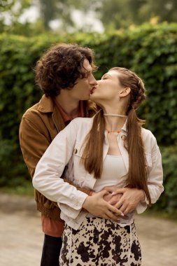 Sevgi dolu genç bir çift parkta romantik bir yürüyüş yaparken tutkuyla kucaklaşır..