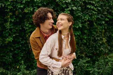 Sevgi dolu bir çift, yemyeşil çimenliklerle çevrili bir parkta gülüşünü ve neşesini paylaşır..