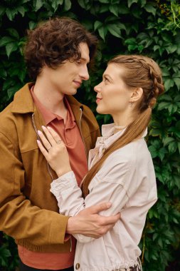 Sevgi dolu genç bir çift, yeşil yaprakların arasında gülücükler ve neşe paylaşıyor..