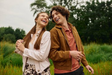 İki genç aşık, yemyeşil yemyeşil ışığın altında keyifli bir yürüyüşü paylaşıyor..