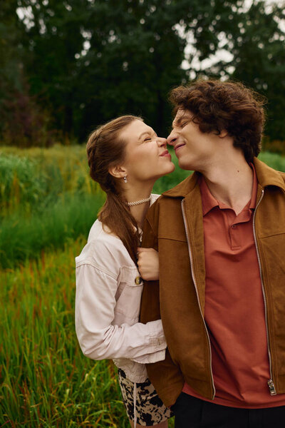 Young couple shares a tender moment while walking together in a lush park environment.