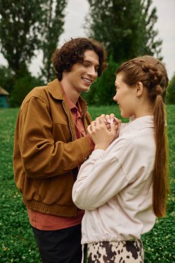 Bir çift el ele yürür, yeşilliklerle çevriliyken neşe ve şefkat saçar..