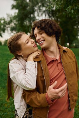 Sevgi dolu bir çift birbirine yakın bir şekilde dolaşır, canlı yeşil bir parkta neşeli anlar paylaşır..