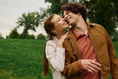 İki aşık, açık havada aşklarını kucaklayarak, sakin bir parkta yürürken mutlu bir anı paylaşırlar..