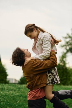 Genç bir çift, yemyeşil bir parkta el ele yürürken birbirlerine eşlik etmekten zevk alır..