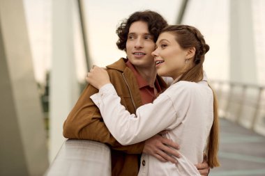 Bir erkek ve kadın birlikte yürürler, yeşilliklerle çevrili iken mutluluğu ve bağlantıyı kucaklarlar..