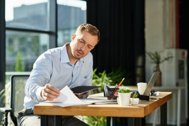 Kendini işine adamış genç bir profesyonel, belgeleri parlak ve modern bir ofiste gözden geçirir..