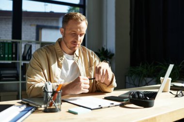 Genç profesyonel evrak ve aletlerle dolu şık bir masadaki görevlere odaklanıyor..