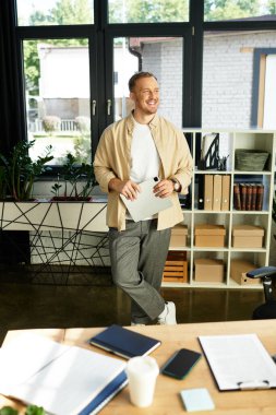 Yakışıklı genç profesyonel, modern bir ofiste, elinde bir belge, ve gülümsüyor..