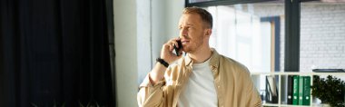 Etkileyici genç bir profesyonel, şık bir ofis ortamında telefonla iletişim kuruyor..