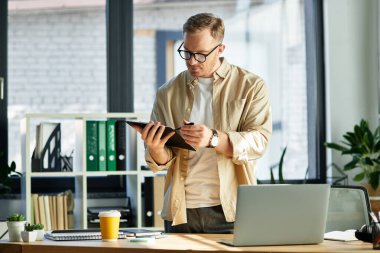 Zarif bir ofiste çalışırken dijital tabletine odaklanmış yakışıklı bir profesyonel..