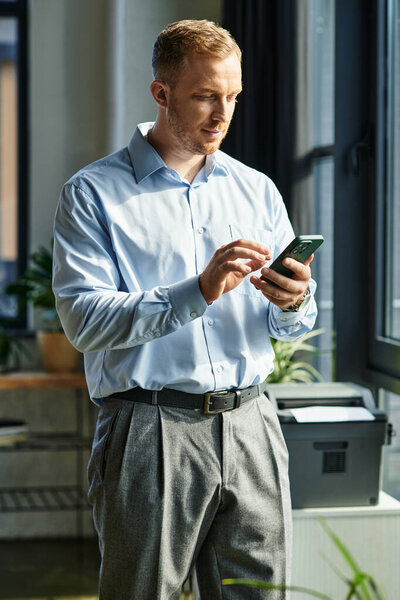 Молодой профессионал использует смартфон в шикарном офисе, подчеркивая производительность.