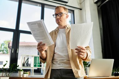 Genç profesyonel raporları parlak bir ofiste analiz eder, kararlılık ve gayret gösterir.
