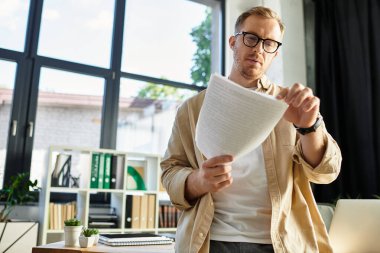 Yakışıklı profesyonel, parlak, şık bir ofis alanında dururken önemli belgeleri analiz eder..