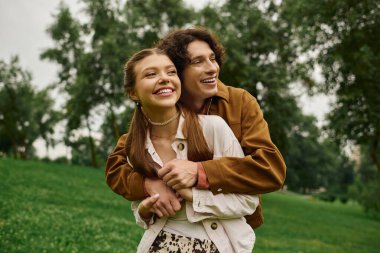 Genç bir çift güzel bir parkta birlikte yürüyor, ağaçların altında gülüşlerini ve sıcaklıklarını paylaşıyorlar..