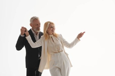 Zarif bir şekilde giyinmiş sevimli çift, parlak bir ışıkta dans ederken neşeli bir anı paylaşıyor..