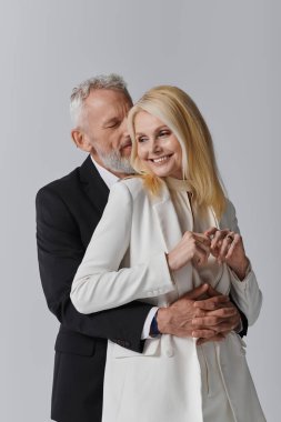 Çekici bir son sınıf çifti, şık kıyafetlerini ve sevgilerini göstererek sevgiyle kucaklaşır..