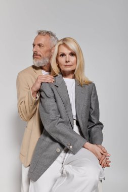 Şık kıyafetlerle poz veren çift, tarafsız bir arkaplanda aşklarını sergiliyorlar..