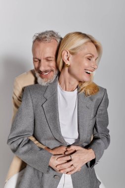 Sevgi dolu üst düzey bir çift birbirine sarılır, şık giyinirken neşe ve şefkat saçar..