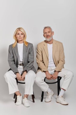 Sevgi dolu yaşlı bir çift birbirine yakın oturur, şık kıyafetlerini ve derin bağlantılarını sergilerler..