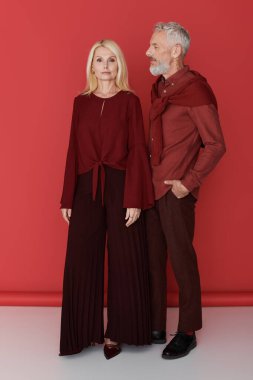 Çekici bir çift, cesur bir arkaplana karşı canlı kıyafetler içinde aşk yayar..