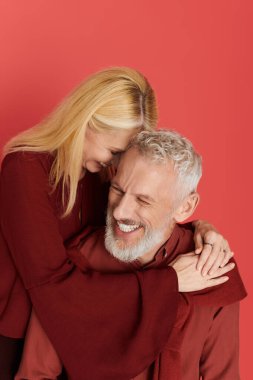 Üst düzey bir çift, canlı bir arkaplan karşısında şık kıyafetler içinde neşe saçıyor..