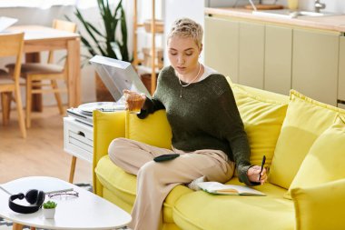 Genç bir kadın evde çayını yudumlarken, defterine yazarken ve kanepede dinlenirken eğleniyor..